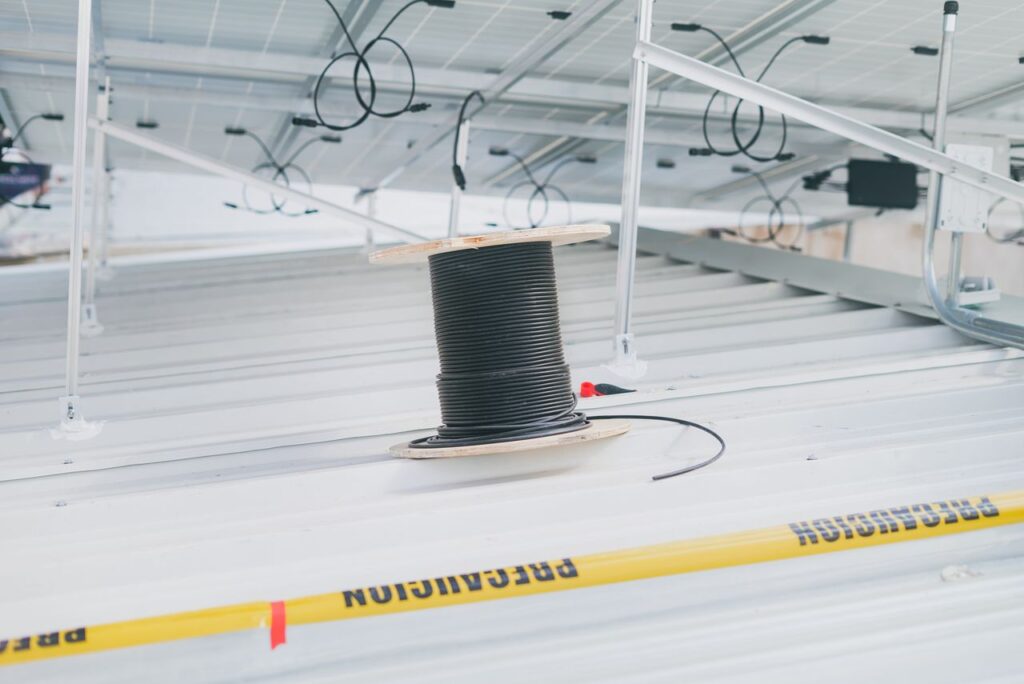 Coiled cable on a rooftop with solar panels, showcasing electrical installation for renewable energy.